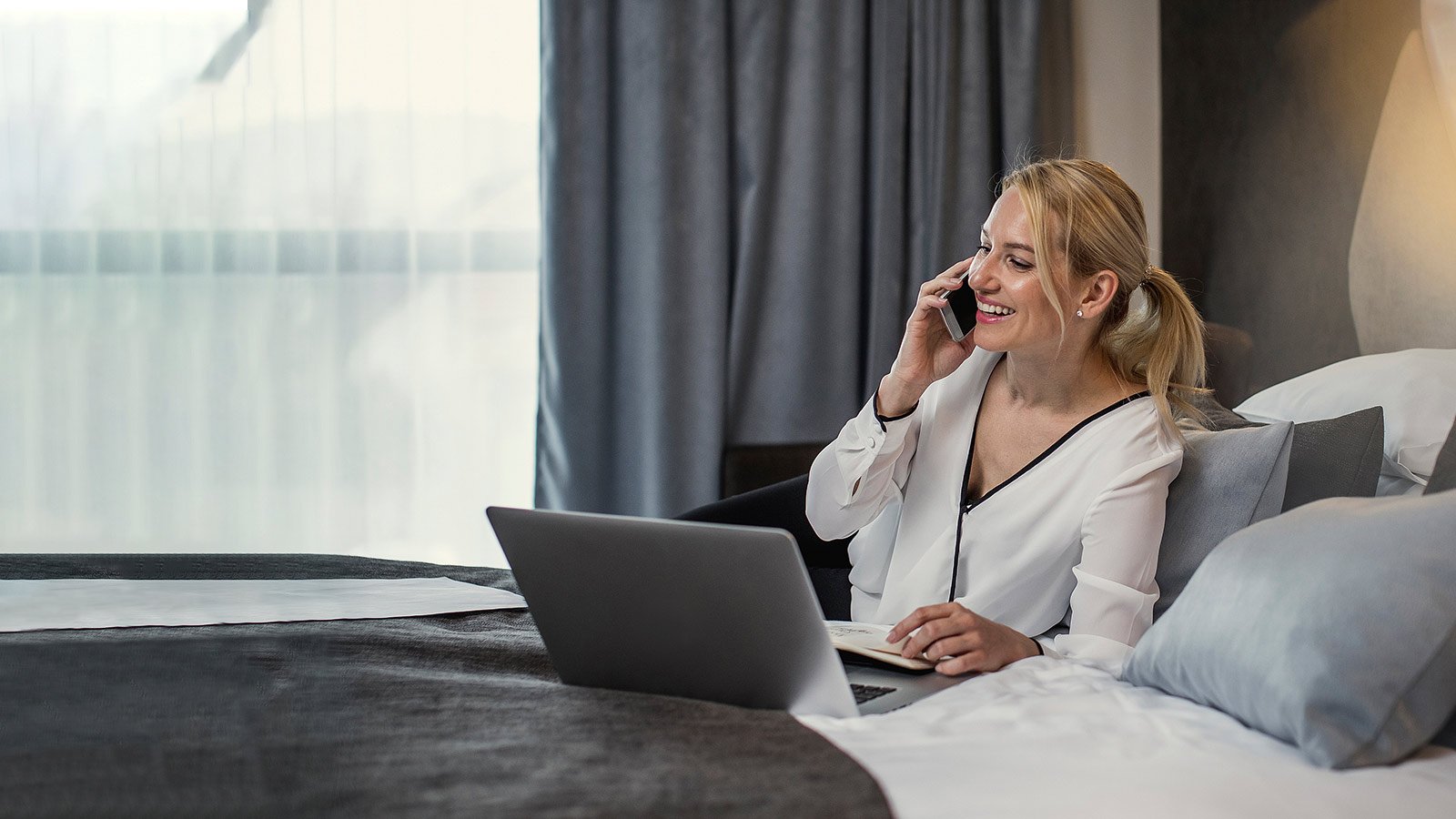 Mujer trabajando con su computadora mientras habla por celular